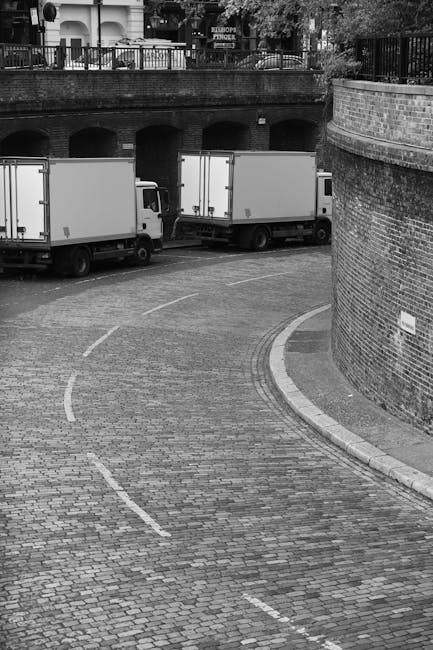 The image shows an outdoor urban scene near the Barbican Centre, featuring a concrete area with several large, rectangular stone planters or barriers in the foreground. Behind these, there are multipl
